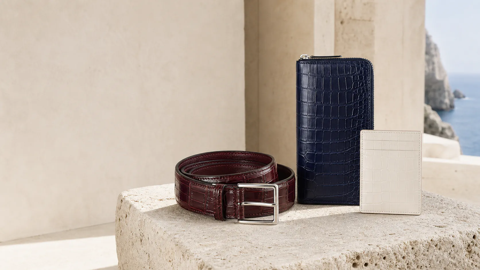 Red crocodile belt, midnight wallet, and ivory card holder on Italian stone